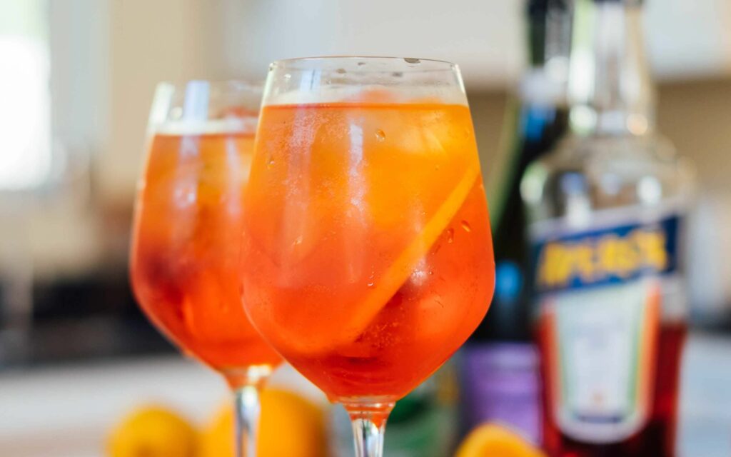 Aperol Spritz Drinks vor einer Original-Flasche Aperol.