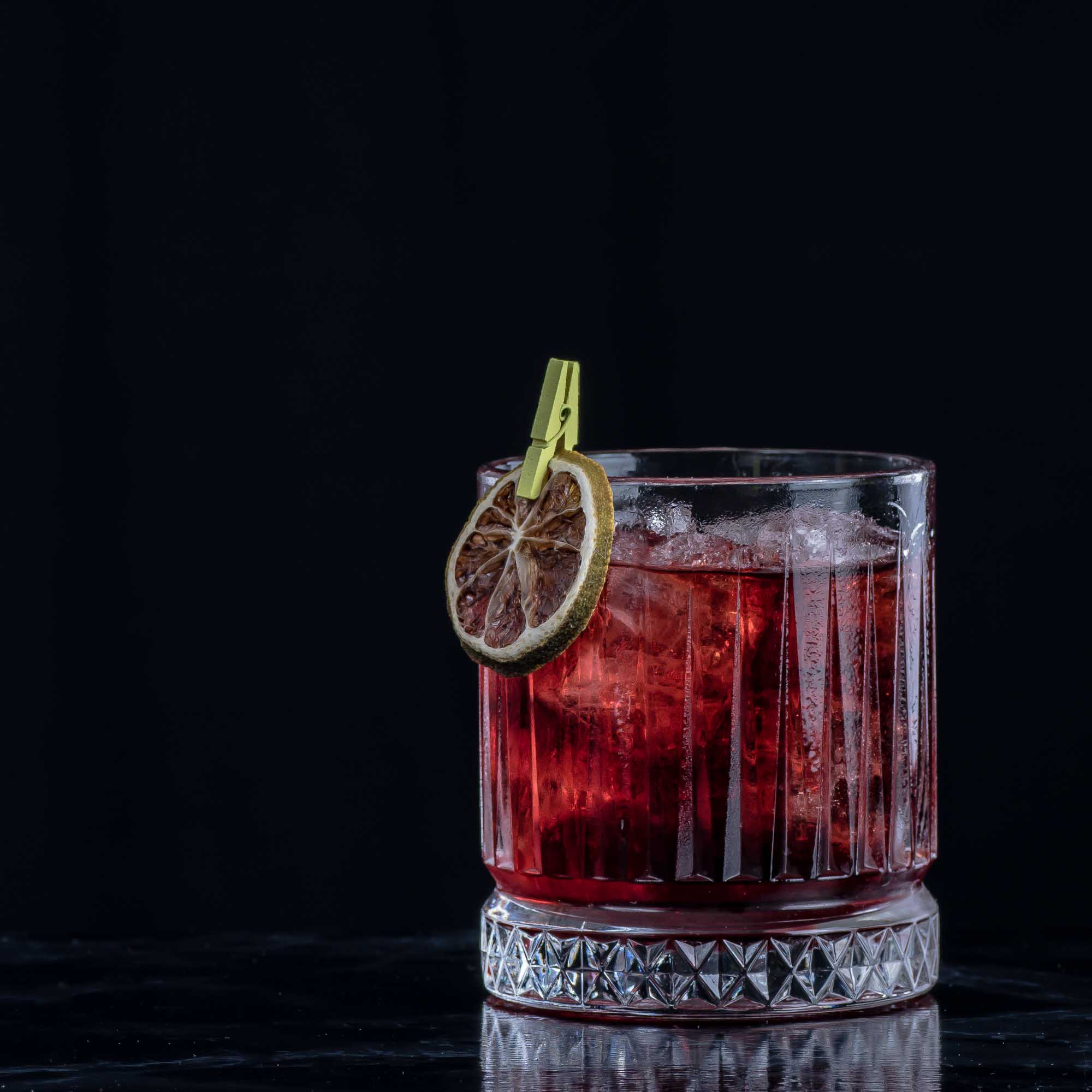 Ein Tumbler mit einem Negroni-Cocktail.