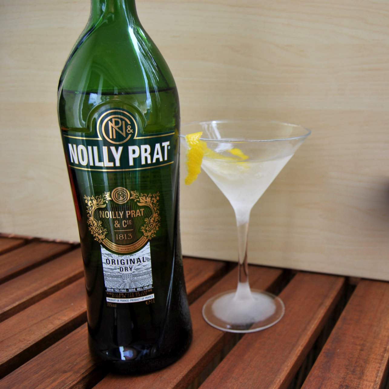 Eine Flasche Noilly Prat mit einem Martini-Cocktail.